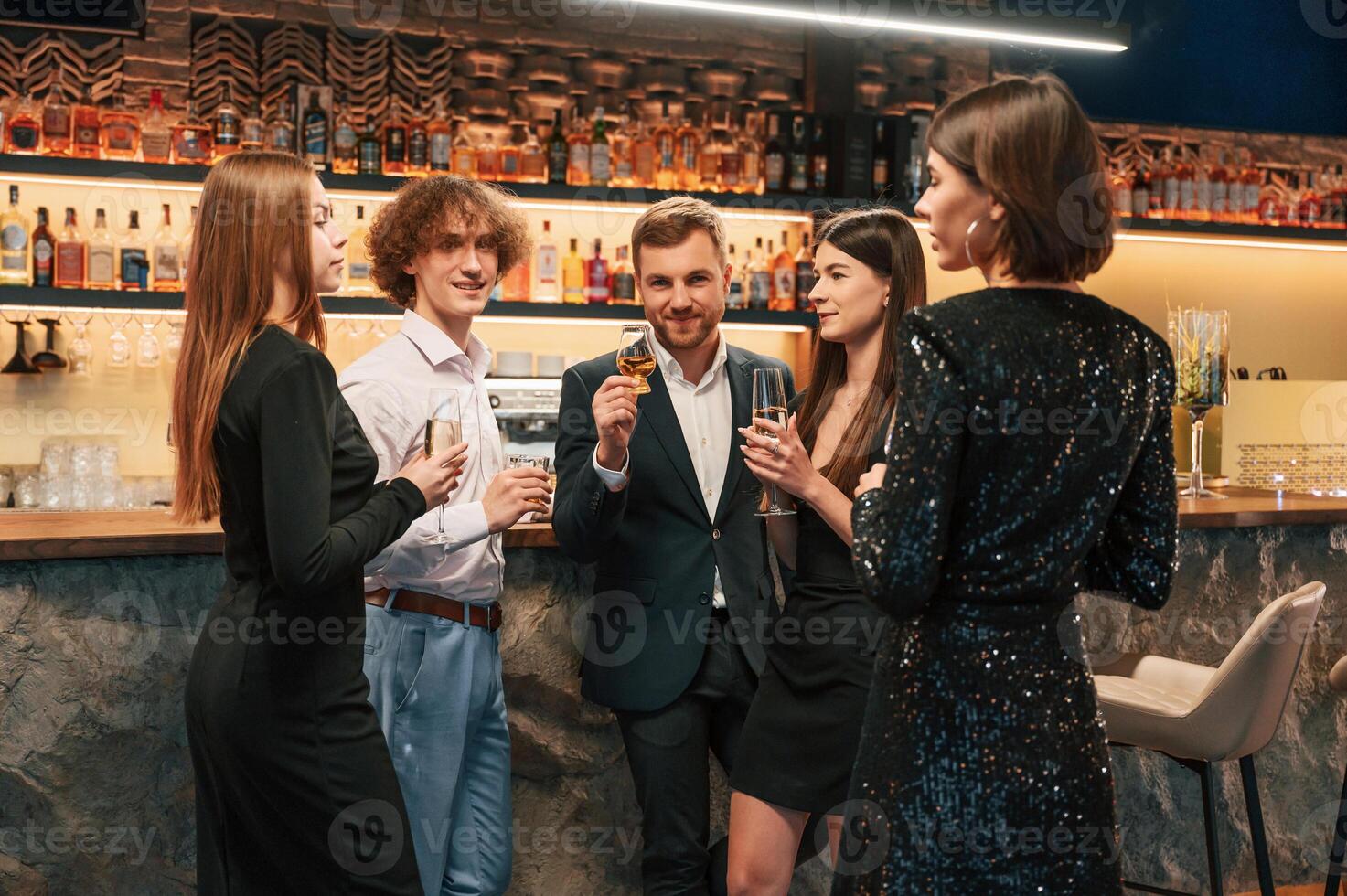 Talking, smiling, having fun. Group ,of people, in beautiful elegant clothes are celebrating New Year indoors together photo