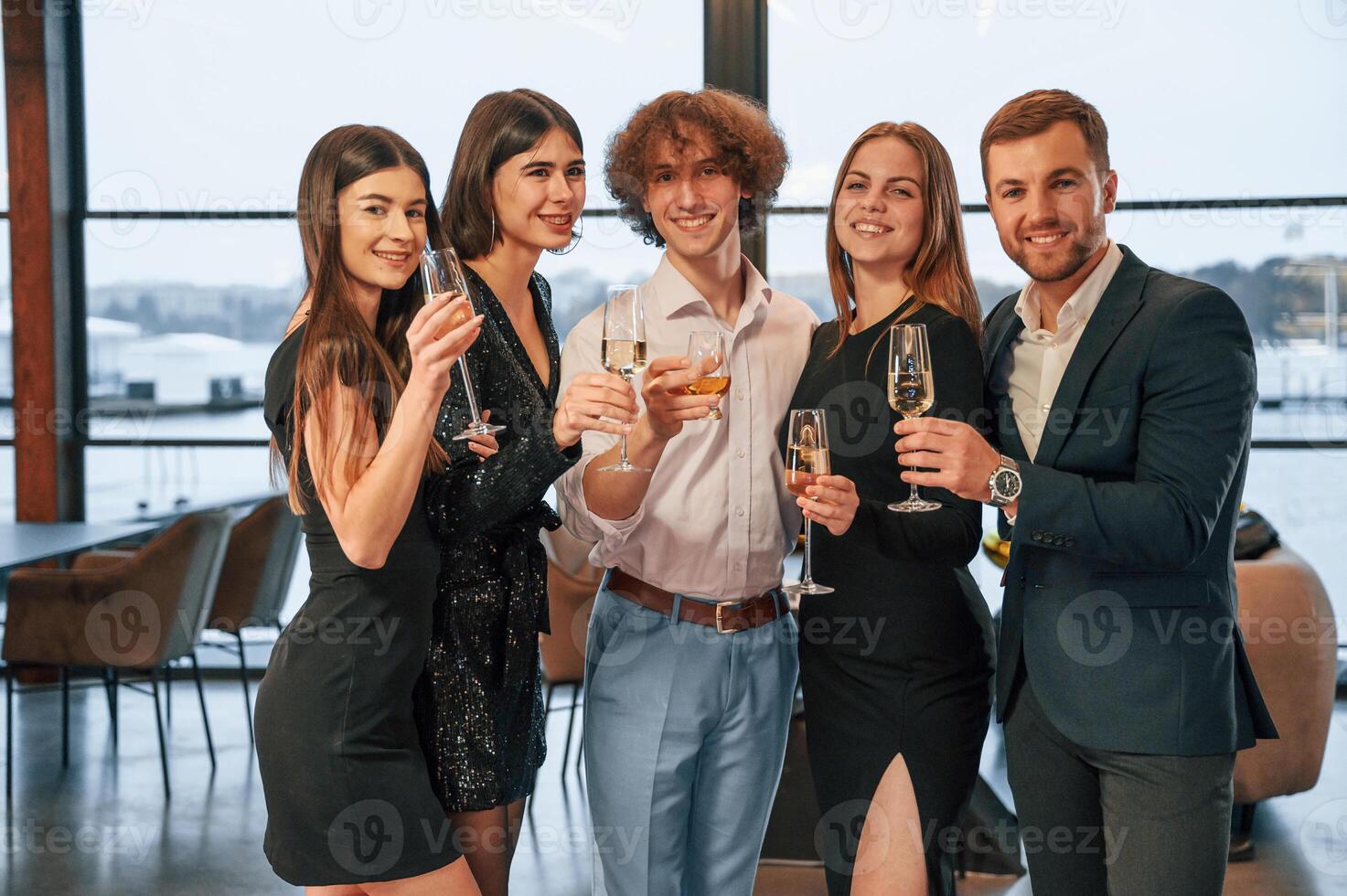 Smiling, for the camera. .Group of people in beautiful elegant clothes are celebrating New Year indoors together photo