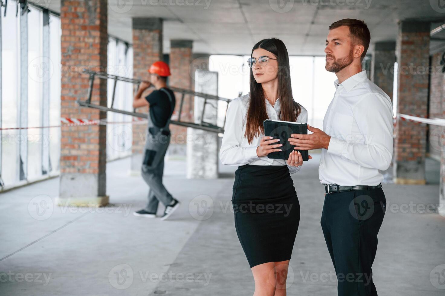Man with ladder at, background. Industry workers are in the building at daytime. Construction location photo