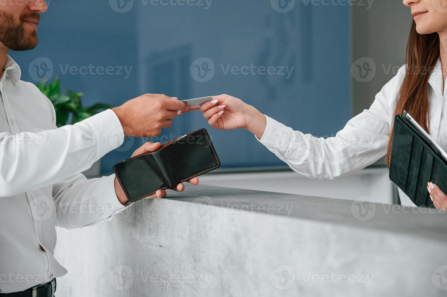 Taking keys at reception. Man in white shirt is ordering a room in the hotel by woman's help photo