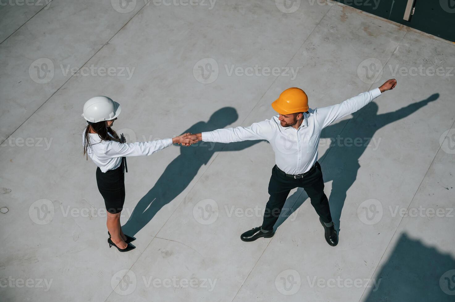 Dancing, having fun. Man with woman are working on the construction project together outside photo