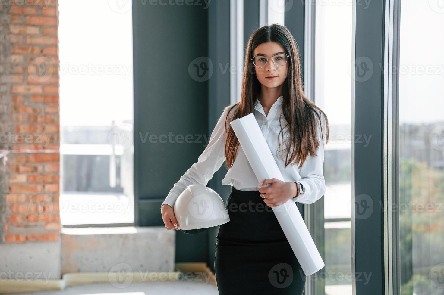 Young, woman, is on the construction site with hard hat and documents photo