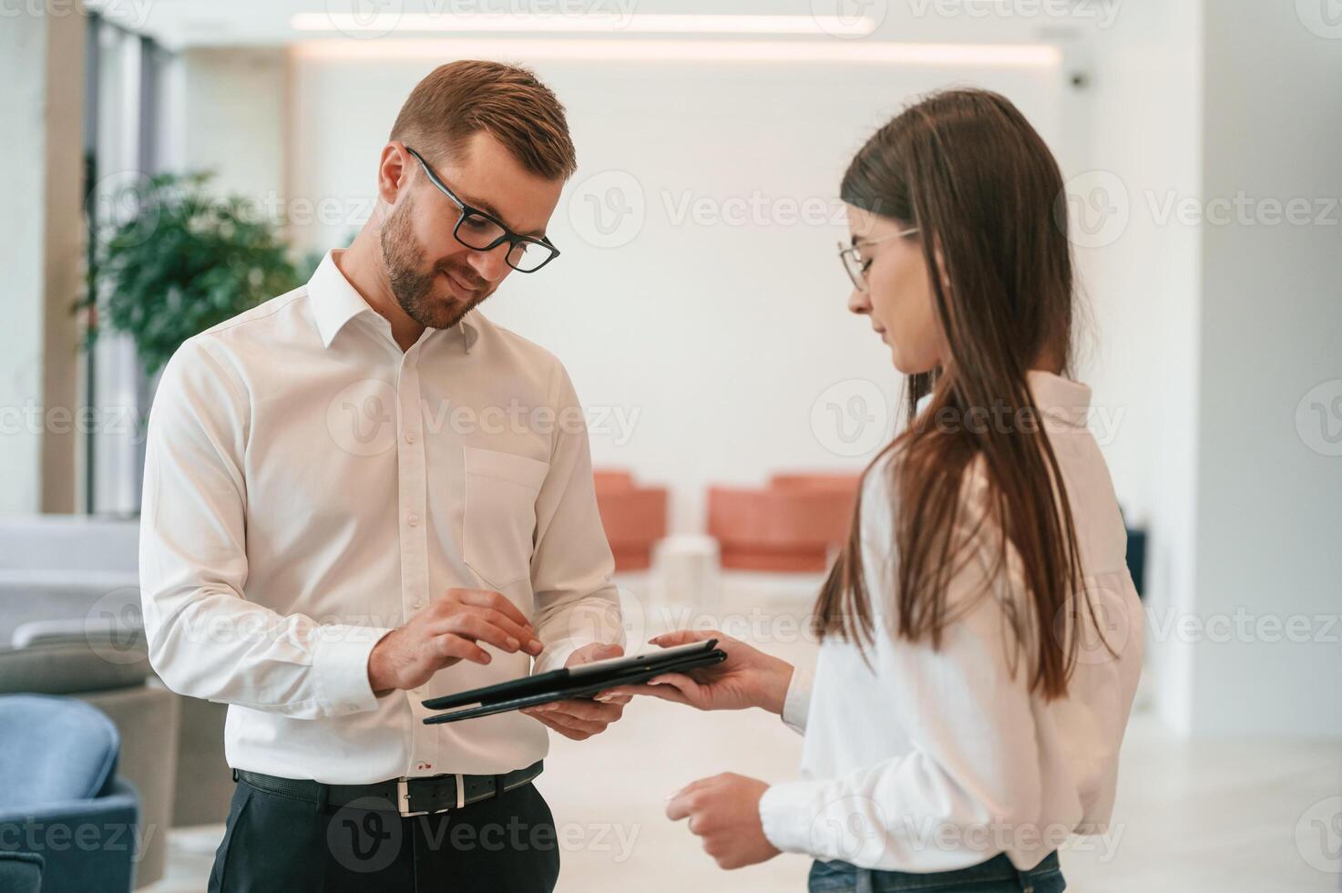 Using digital tablet. Man ,and woman in formal ,clothes are working together indoors photo
