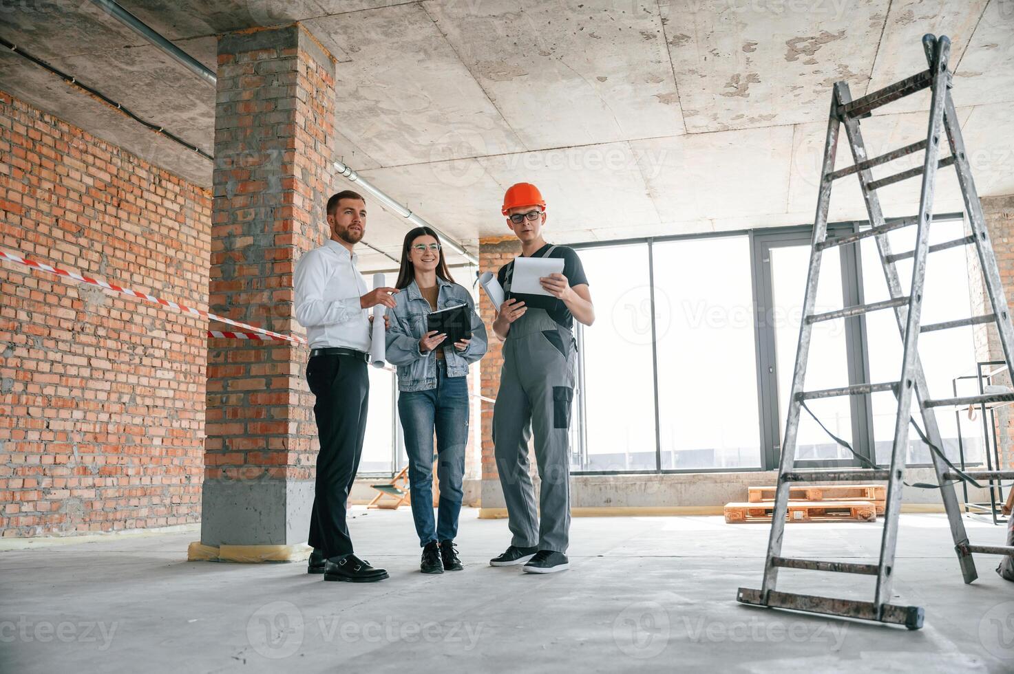 Male manager, foreman and woman is together on the construction site, talking about project photo