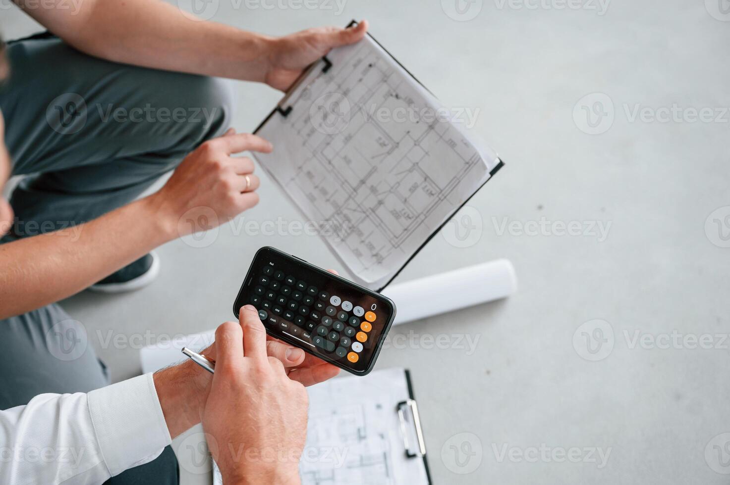 Sitting, using ,calculator. Manager with foreman are working on the construction site together photo