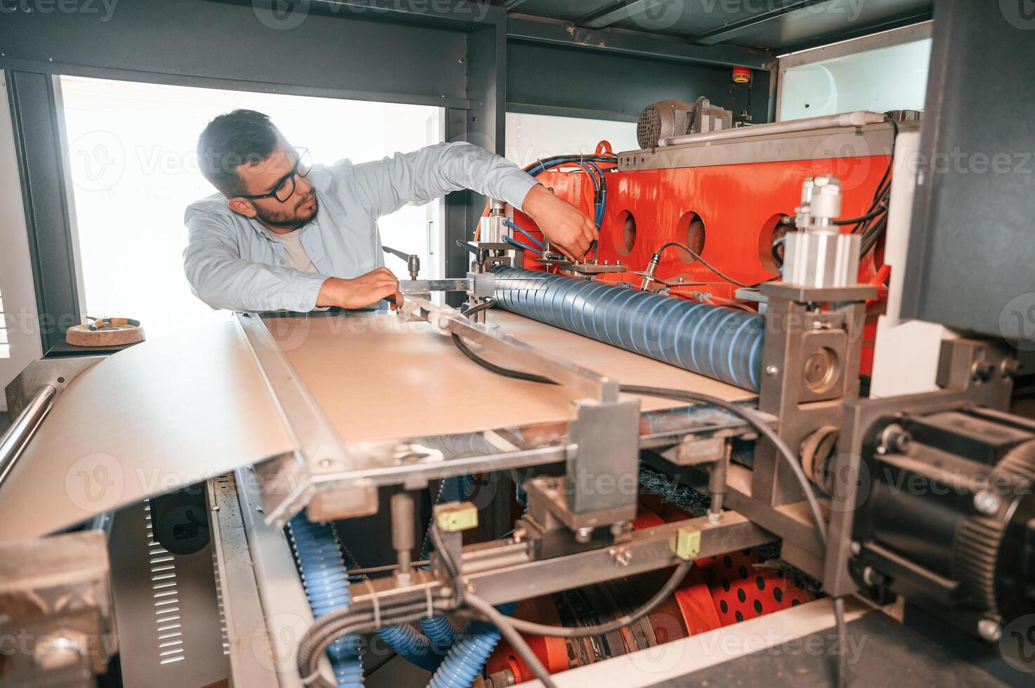 Sheet, cutting machine. Operating device. Print house worker in white clothes is indoors photo