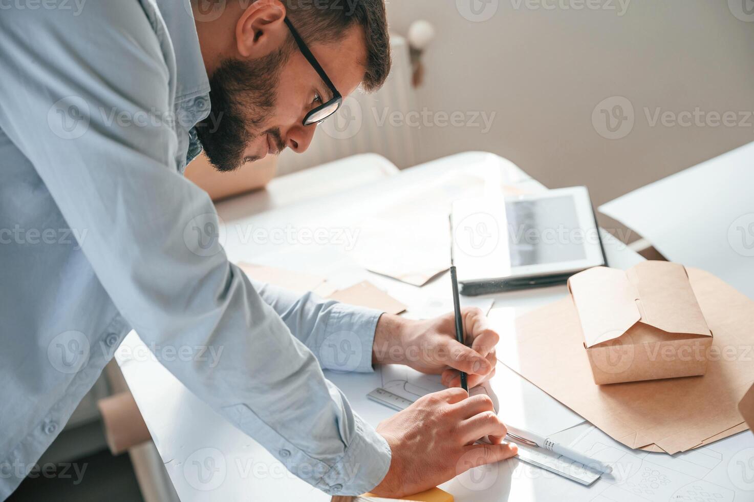 Doing, measurements and drawing new design. Print house worker in white clothes is indoors photo
