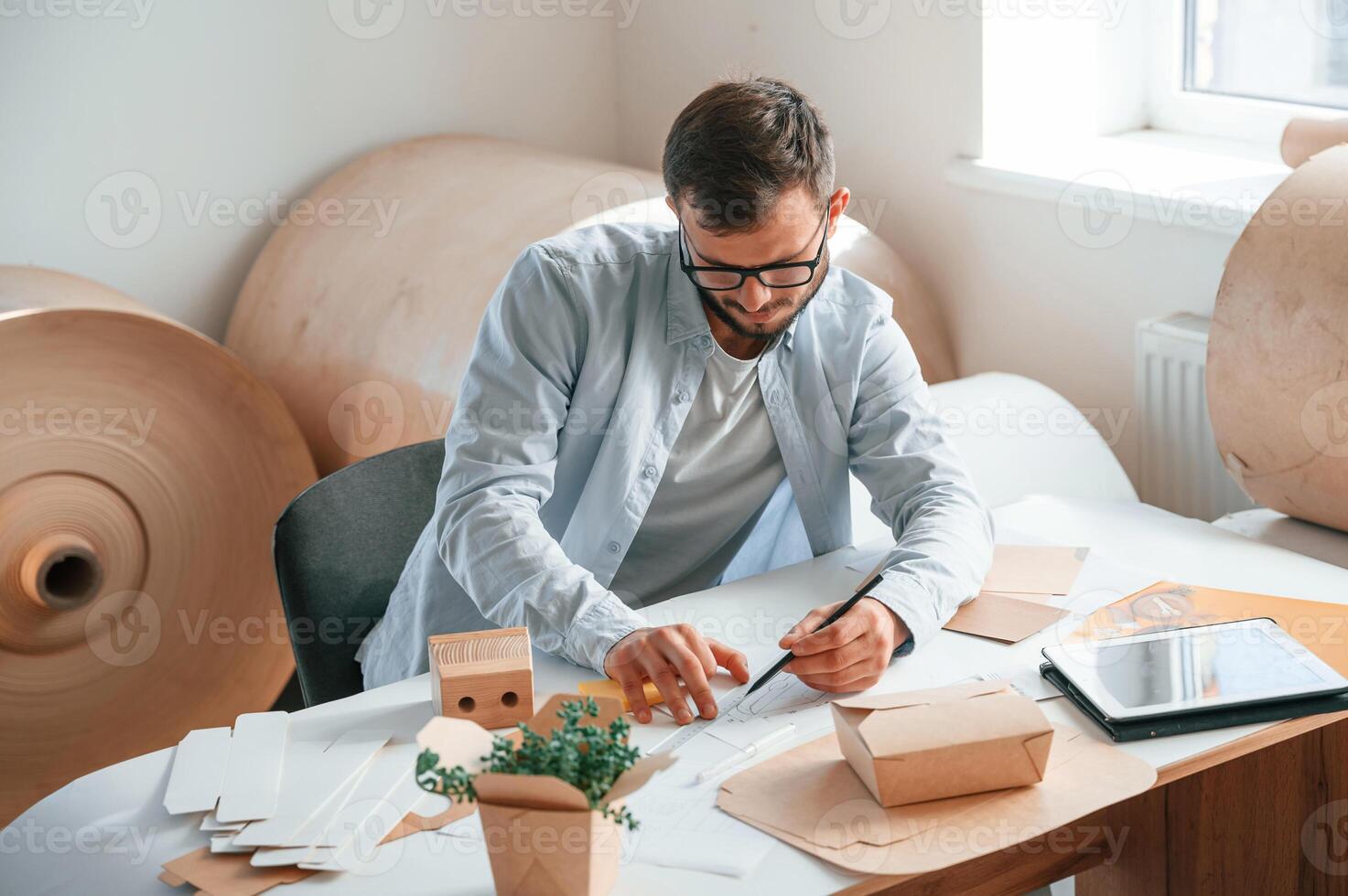 Drawing by the table. Print house, worker in white clothes is indoors photo