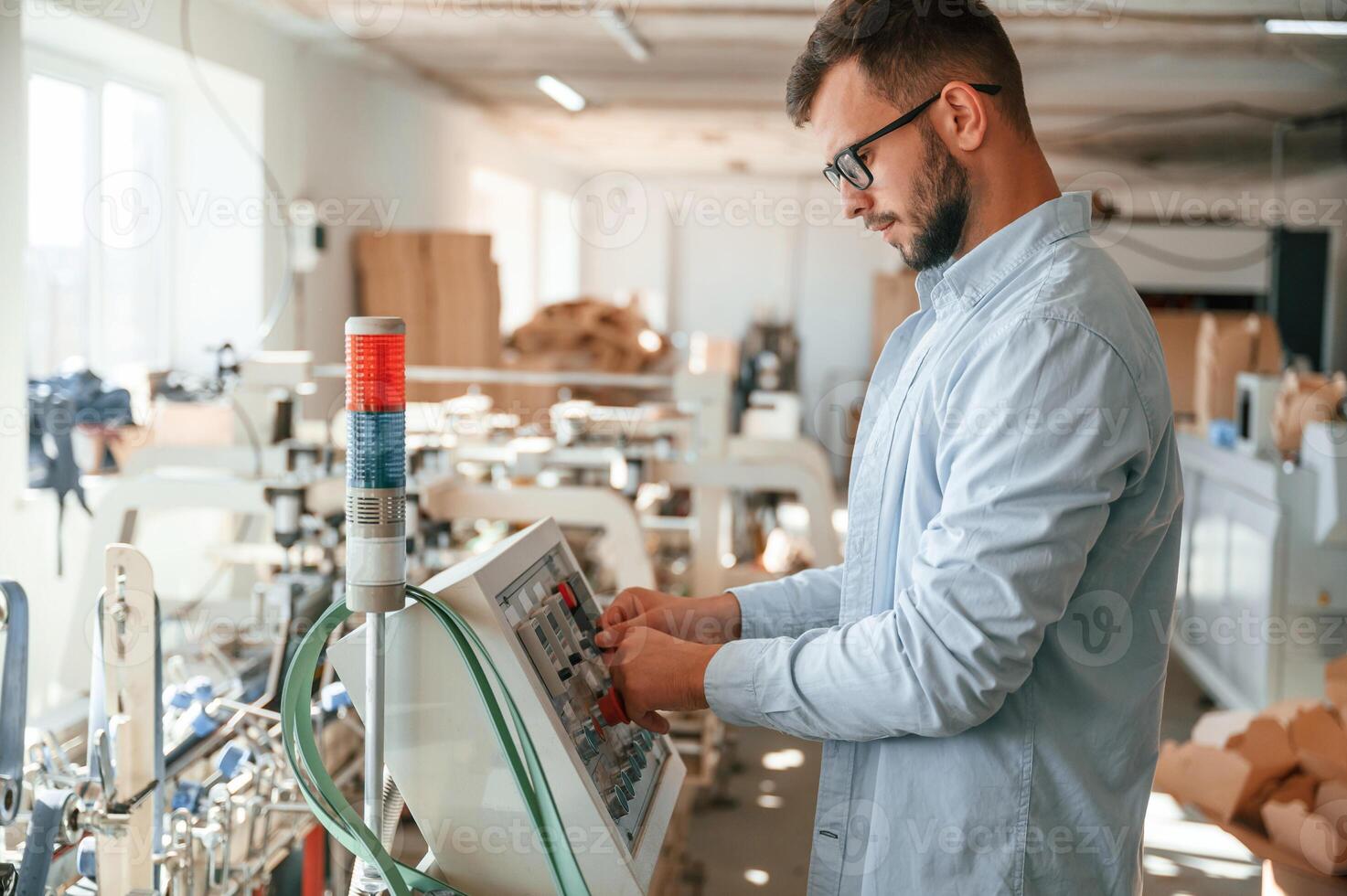 Machine operator ,is busy by setting up a device. Print house worker in white clothes is indoors photo
