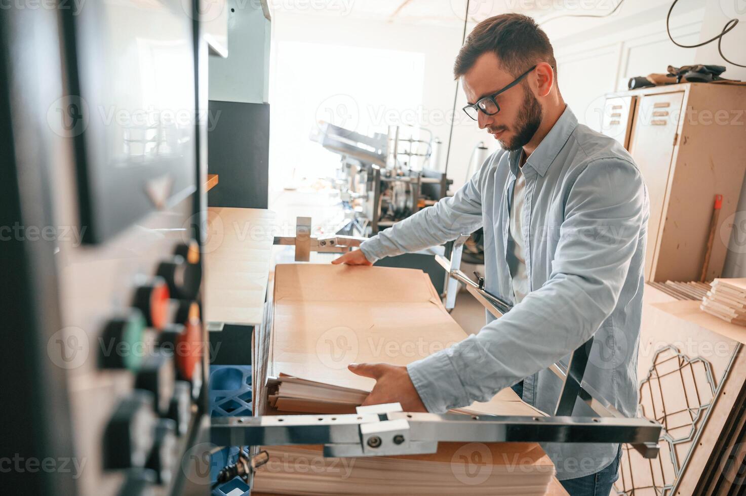 Working ,with wooden sheets. Man in print house that in white clothes is indoors photo
