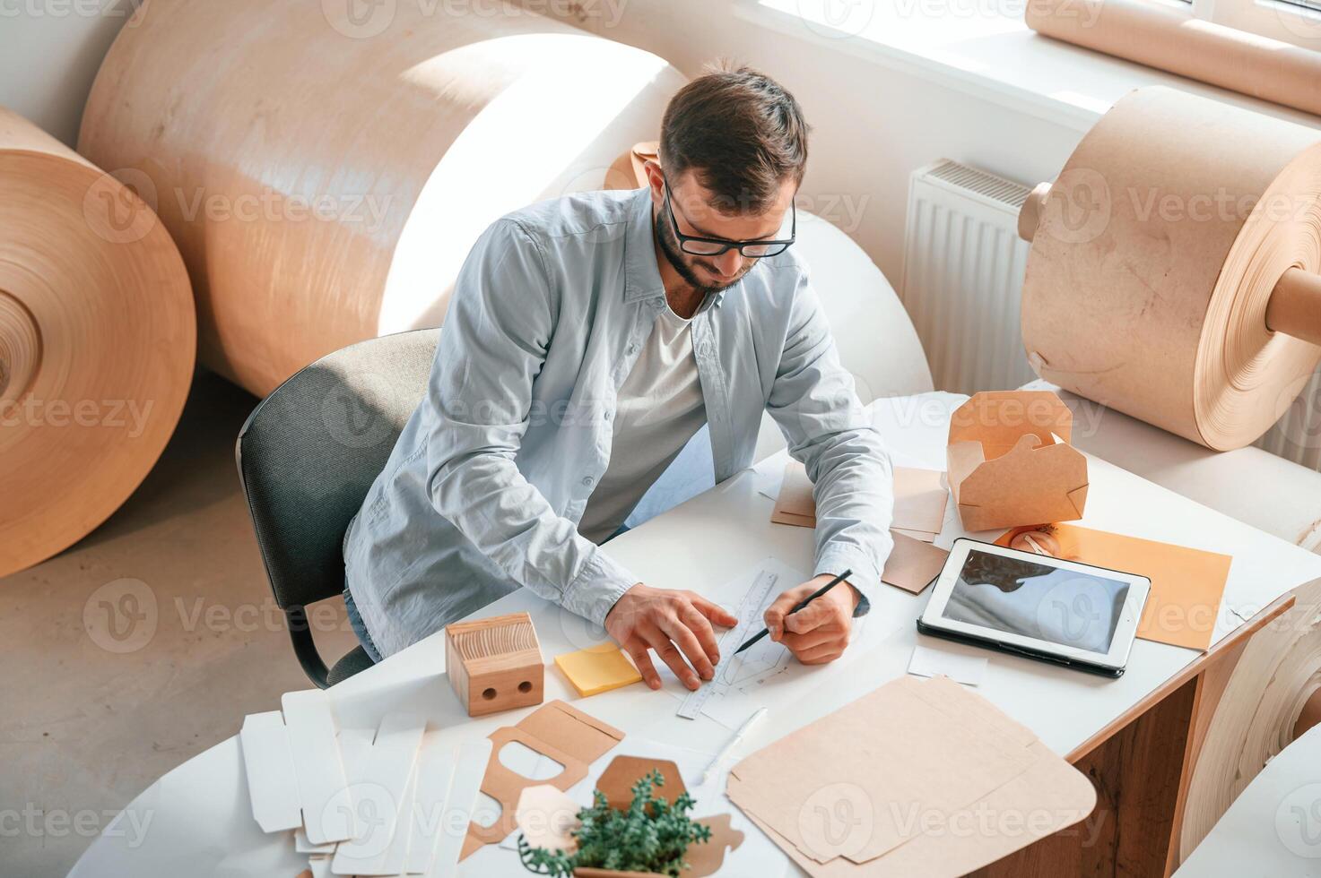 Sitting, and working by the table. Print house employee in white clothes is indoors photo