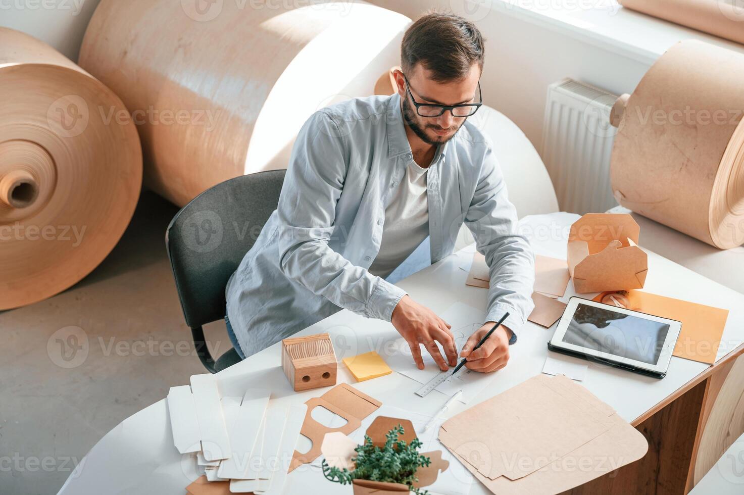 Sitting ,and ,working by the table. Print house employee in white clothes is indoors photo