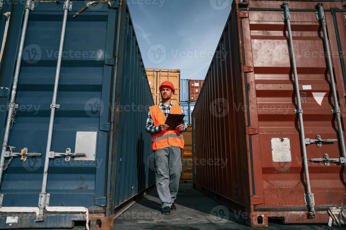 Male ,worker is on the location with containers. Using digital tablet photo