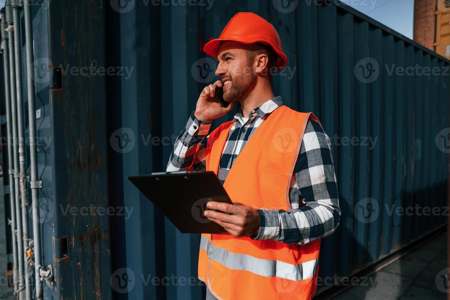Having conversation, by phone. Male worker is on the location with containers photo