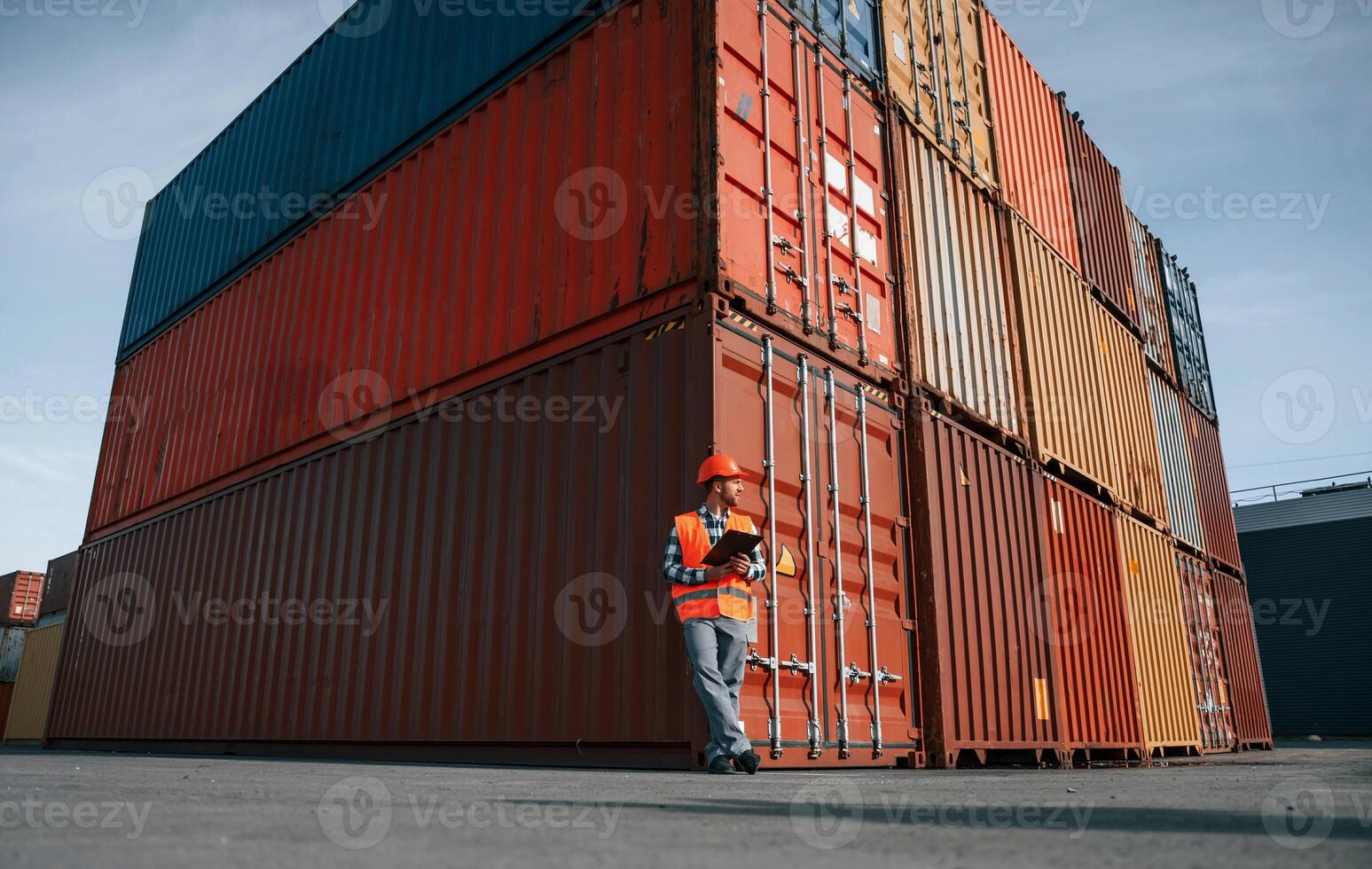 Digital tablet in hands. Male worker, is on the location with containers photo