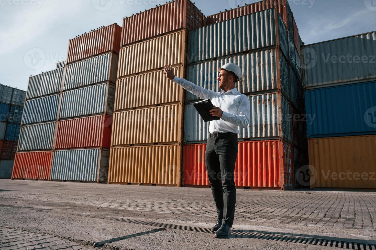 Controlling the process. Holding ,digital tablet. Male worker is on the location with containers photo
