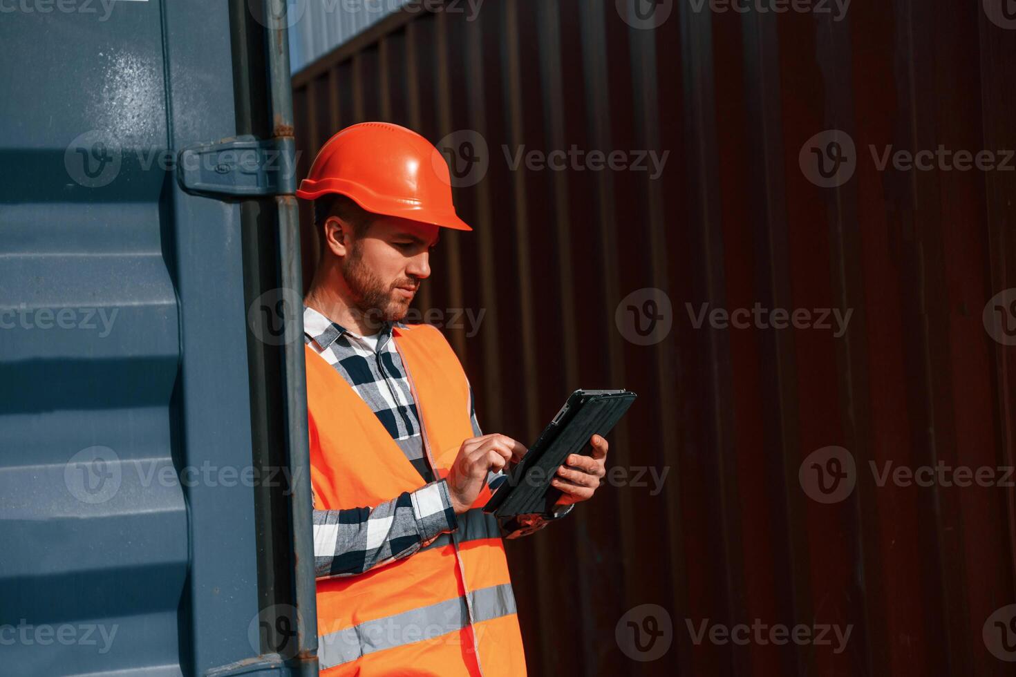 Male ,worker is on ,the location with containers. Using digital tablet photo