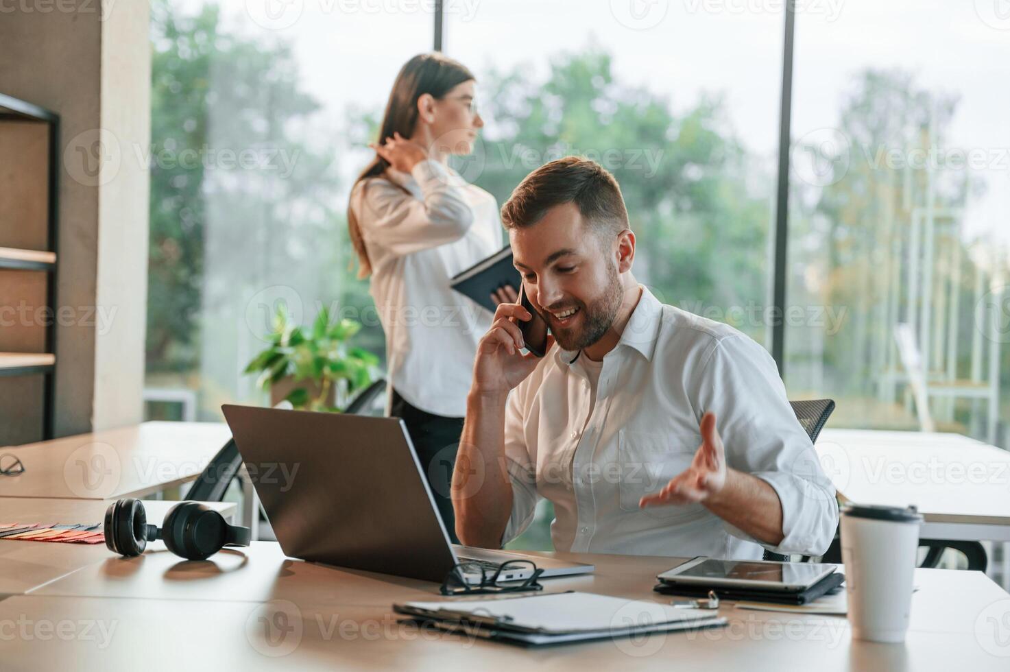 Boss is talking ,by phone. Man and woman are working in the modern office together photo
