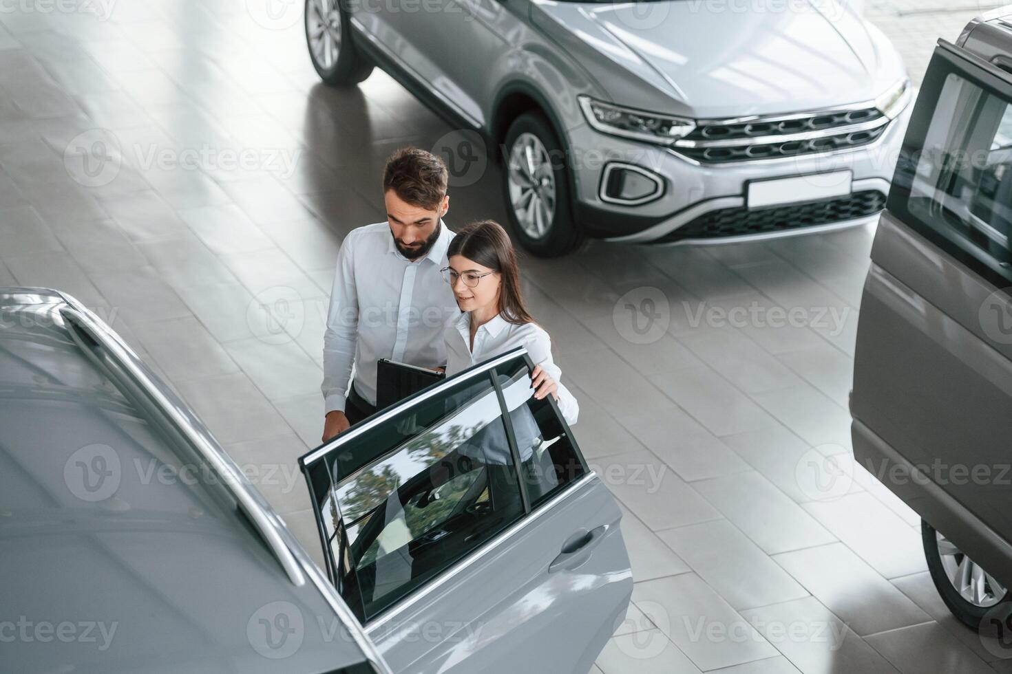 Top view.. Man with woman in white clothes are in the car dealership together photo