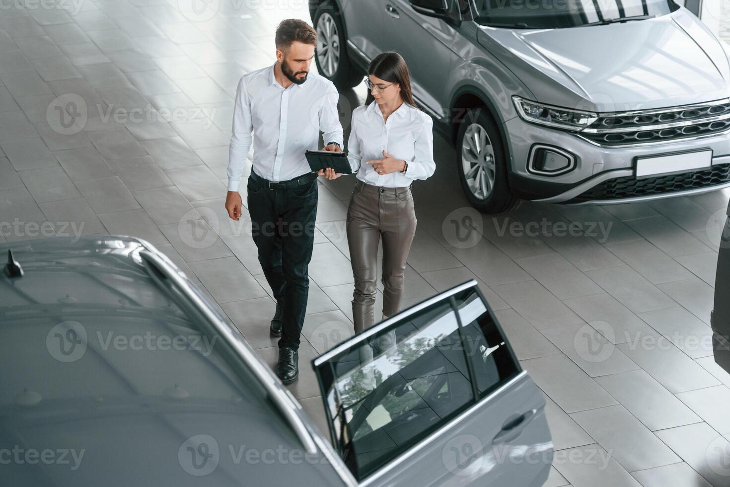 Top view. Man with woman in white clothes ,are in the car dealership together photo