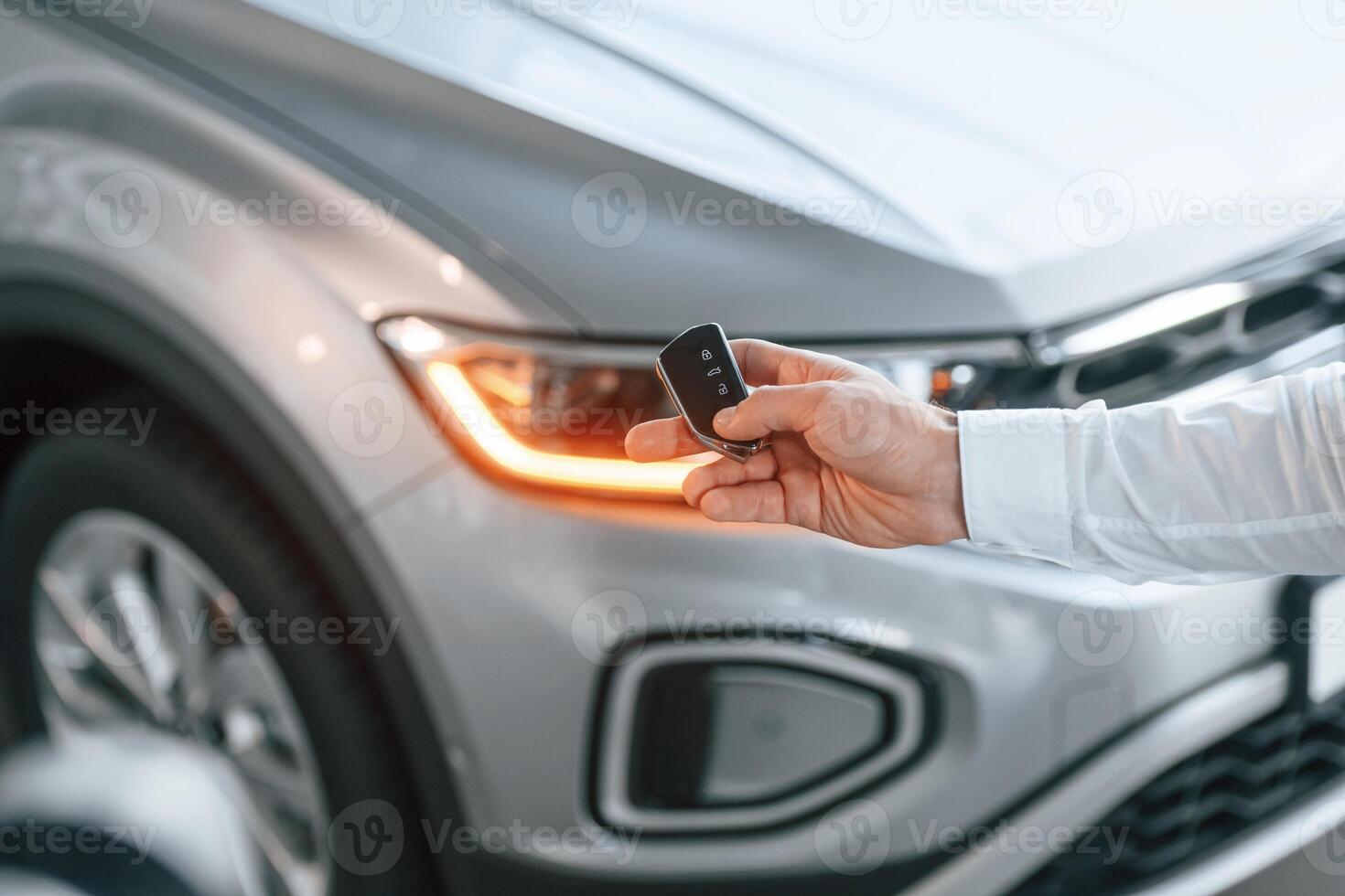 Close ,up view ,of keys. Young man in white clothes is in the car dealership photo
