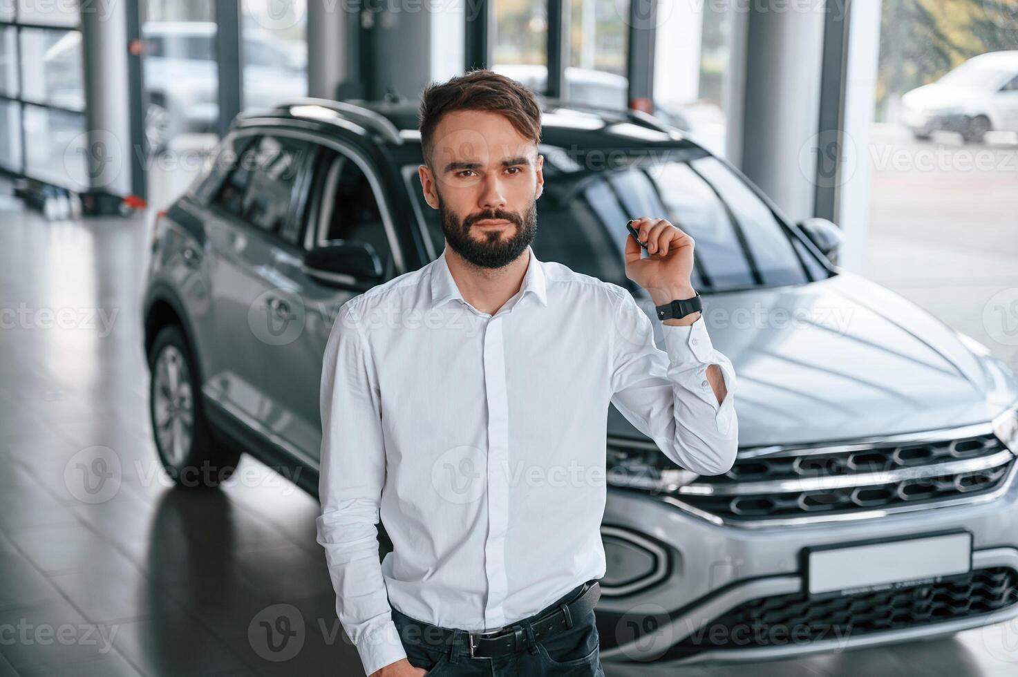 Young ,man ,in white clothes is in the car dealership photo