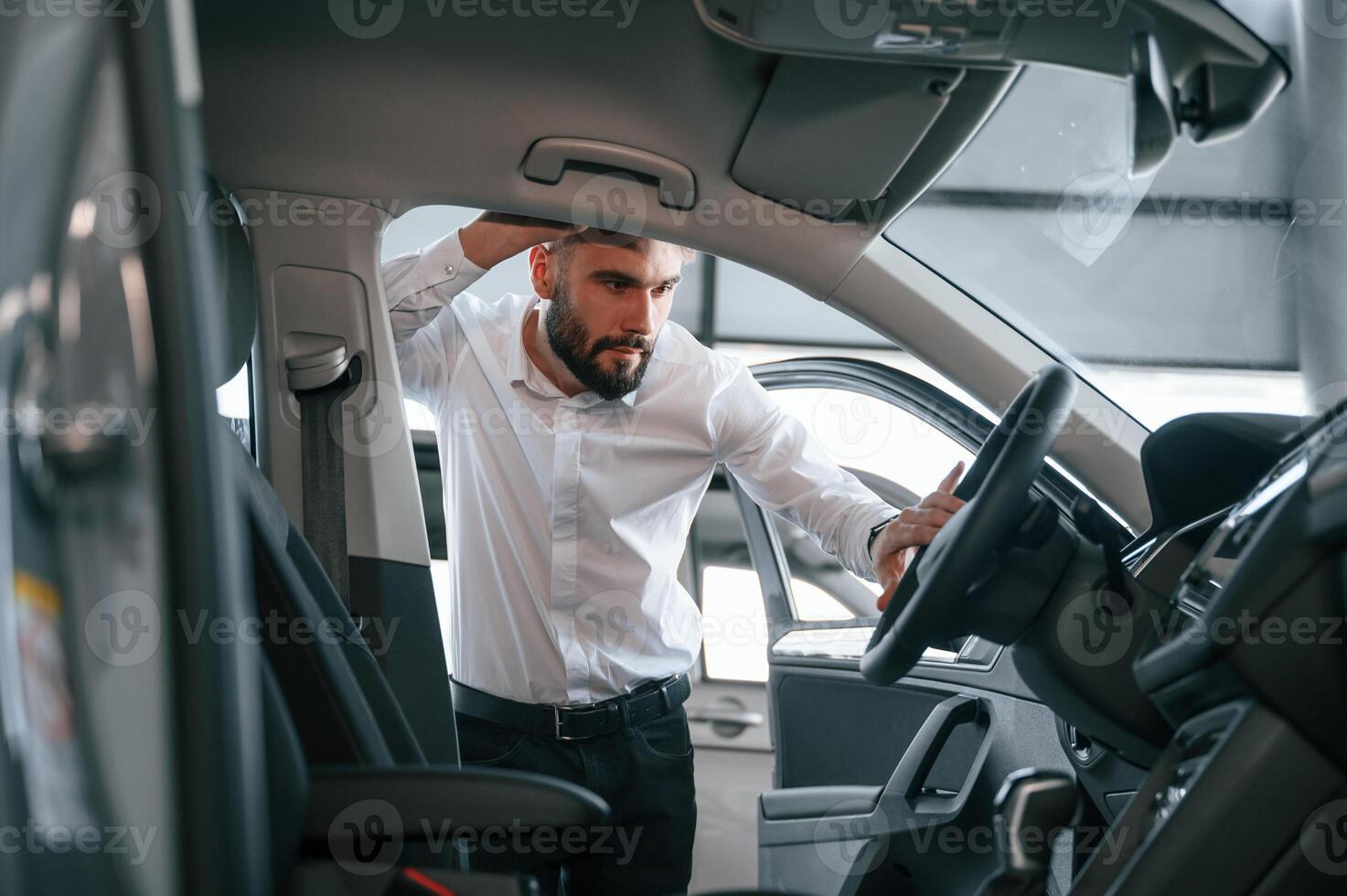 Examining the salon ,of the automobile. Young man in white clothes is in the car dealership photo