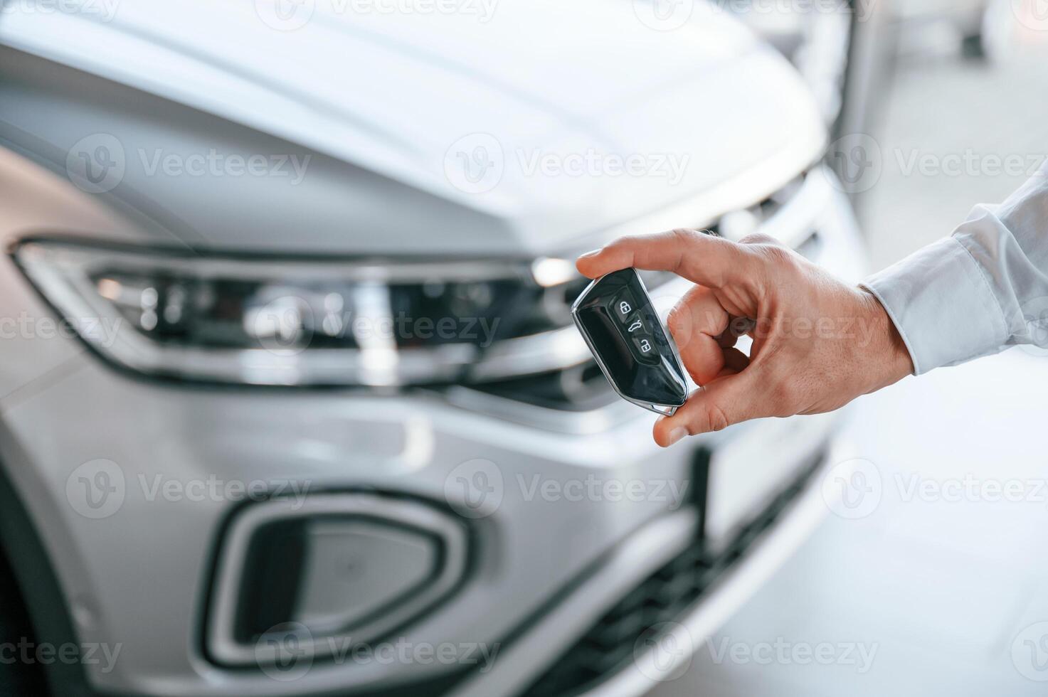 Keys ,and remote controller. Close up view. Young man in white clothes is in the car dealership photo