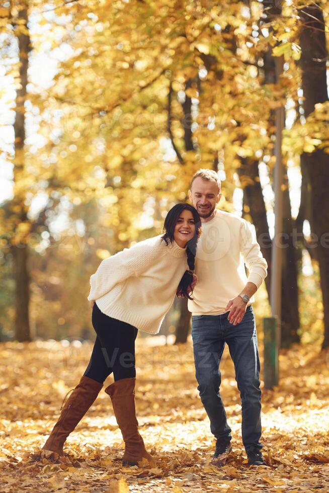 Beautiful couple standing i,n the autumn park at daytime photo