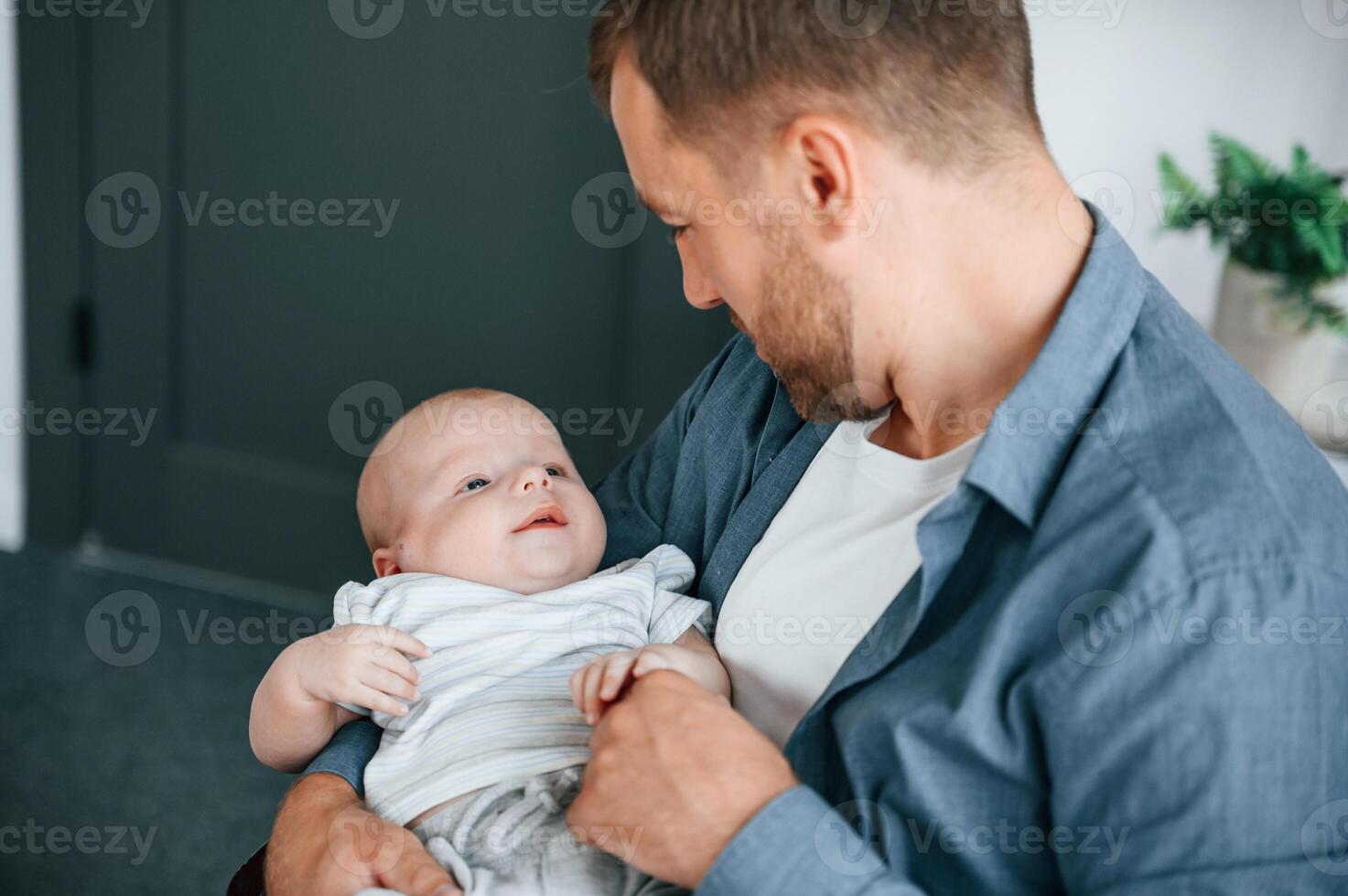 Baby ,is in the hands. Father with toddler is indoors in the office photo
