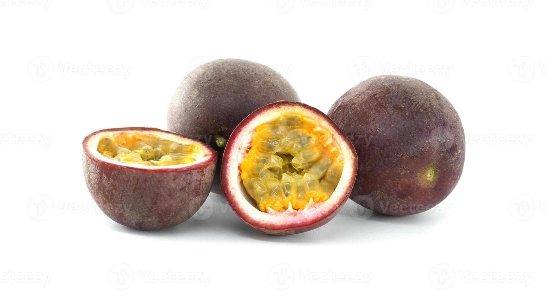 Fresh passion fruits and a half cut passion fruit showing its pulp and seeds on a white background photo