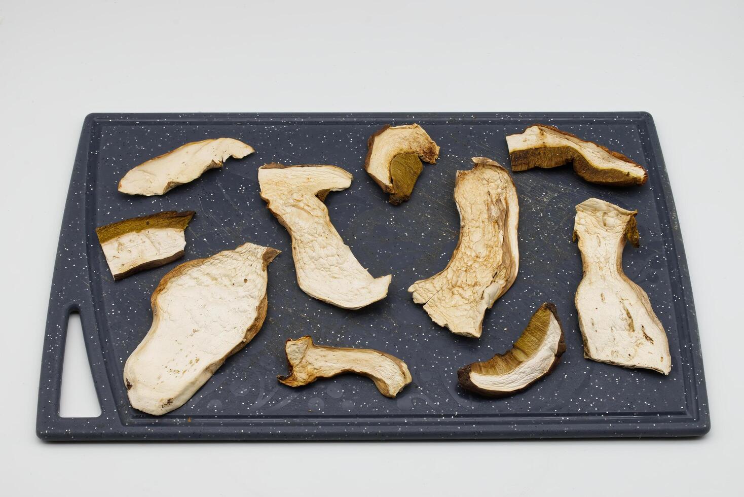 Various dried porcini mushroom slices arranged on a cutting board. photo