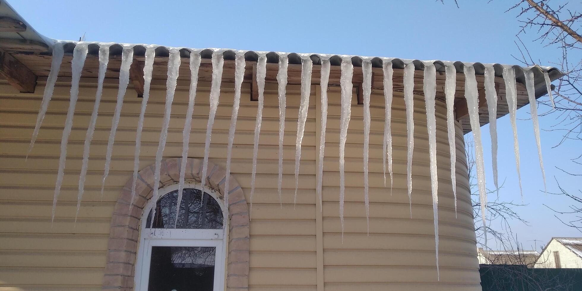 long icicles on the roof of the house photo