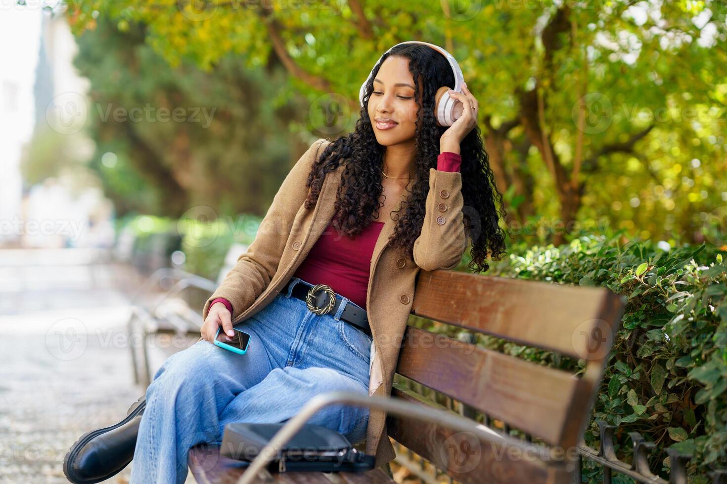 A Young Woman Sitting on a Bench, Enjoying Music in a Peaceful Park Setting, Relaxing photo