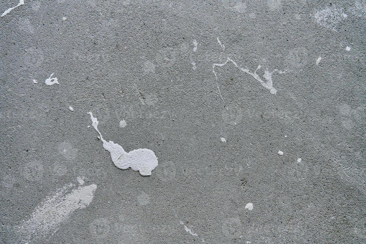 Close-up of concrete wall with white paint splashes and rough texture. Background for construction and renovation concep photo