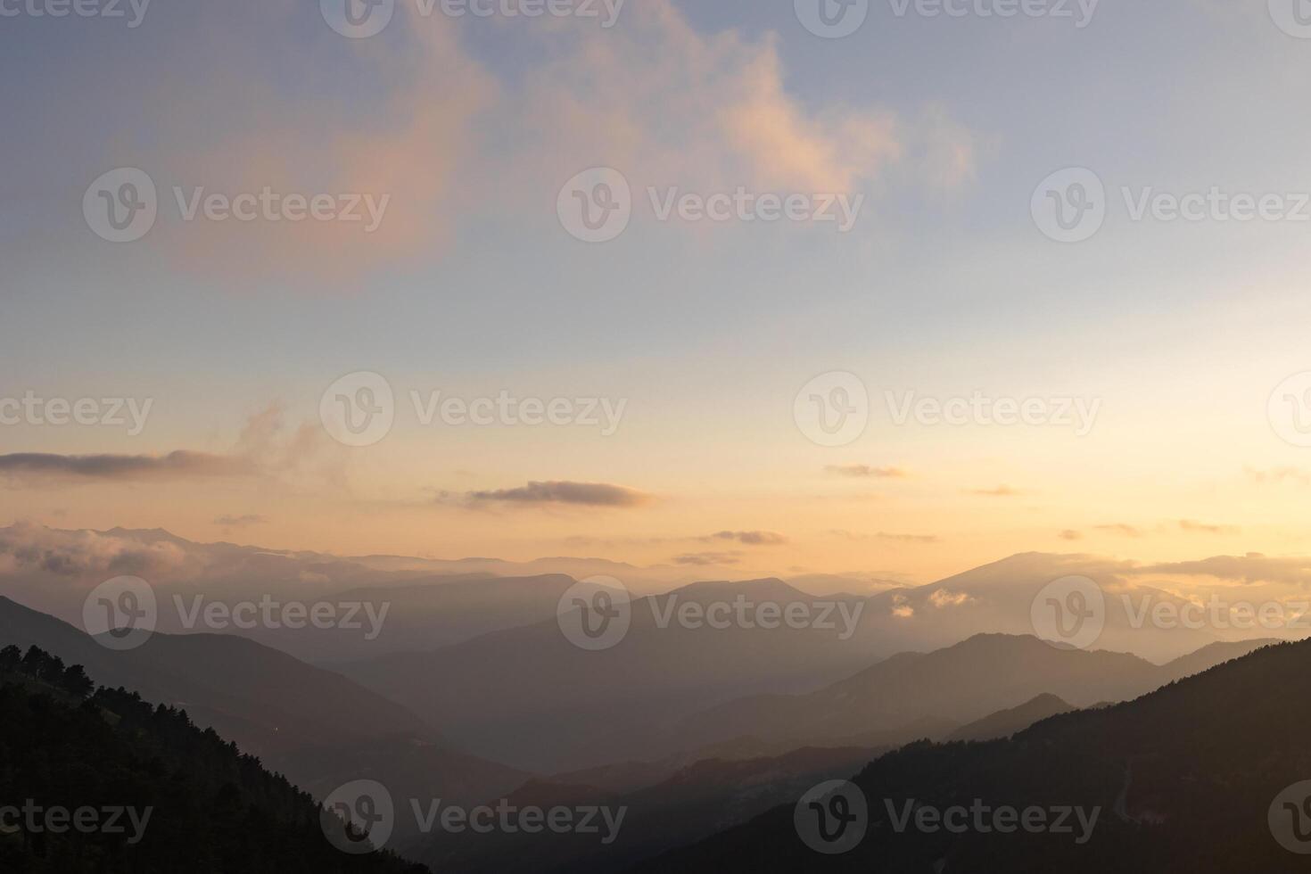 Silhouette of the hazy mountain ranges with fog at sunset. photo