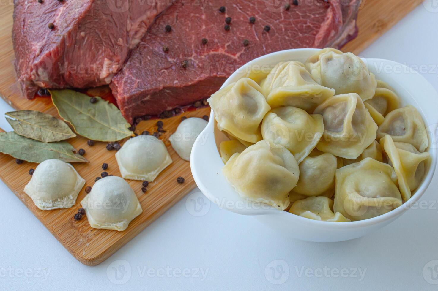 A piece of beef meat and beef dumplings on a kitchen board. A banner with meat products marbled beef peppercorns and bay leaves. High quality photo