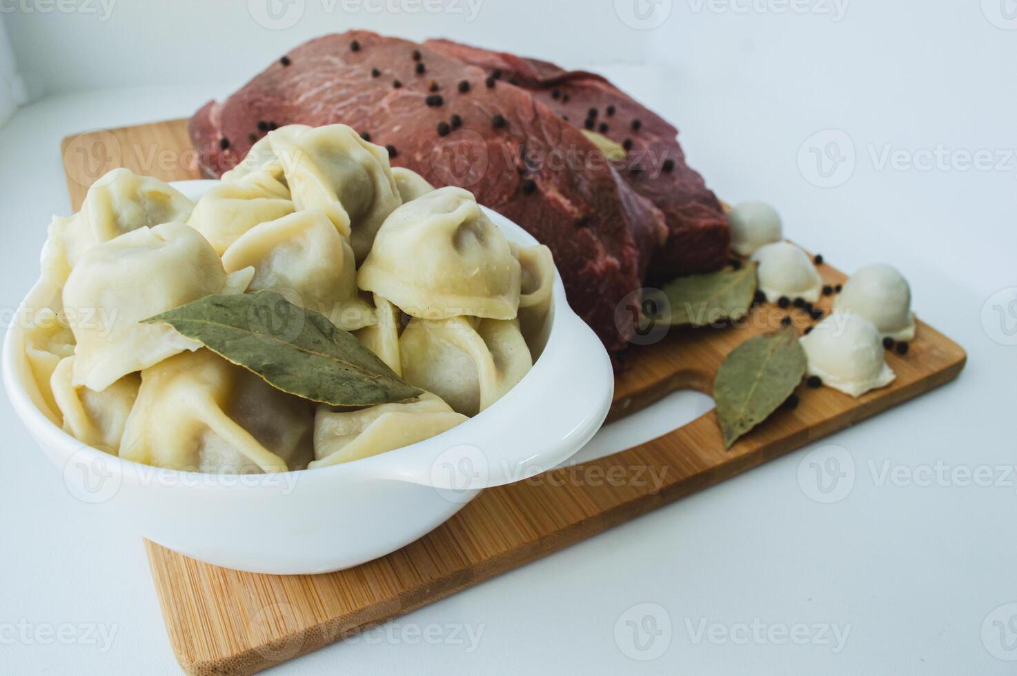 A piece of beef meat and beef dumplings on a kitchen board. A banner with meat products marbled beef peppercorns and bay leaves. High quality photo