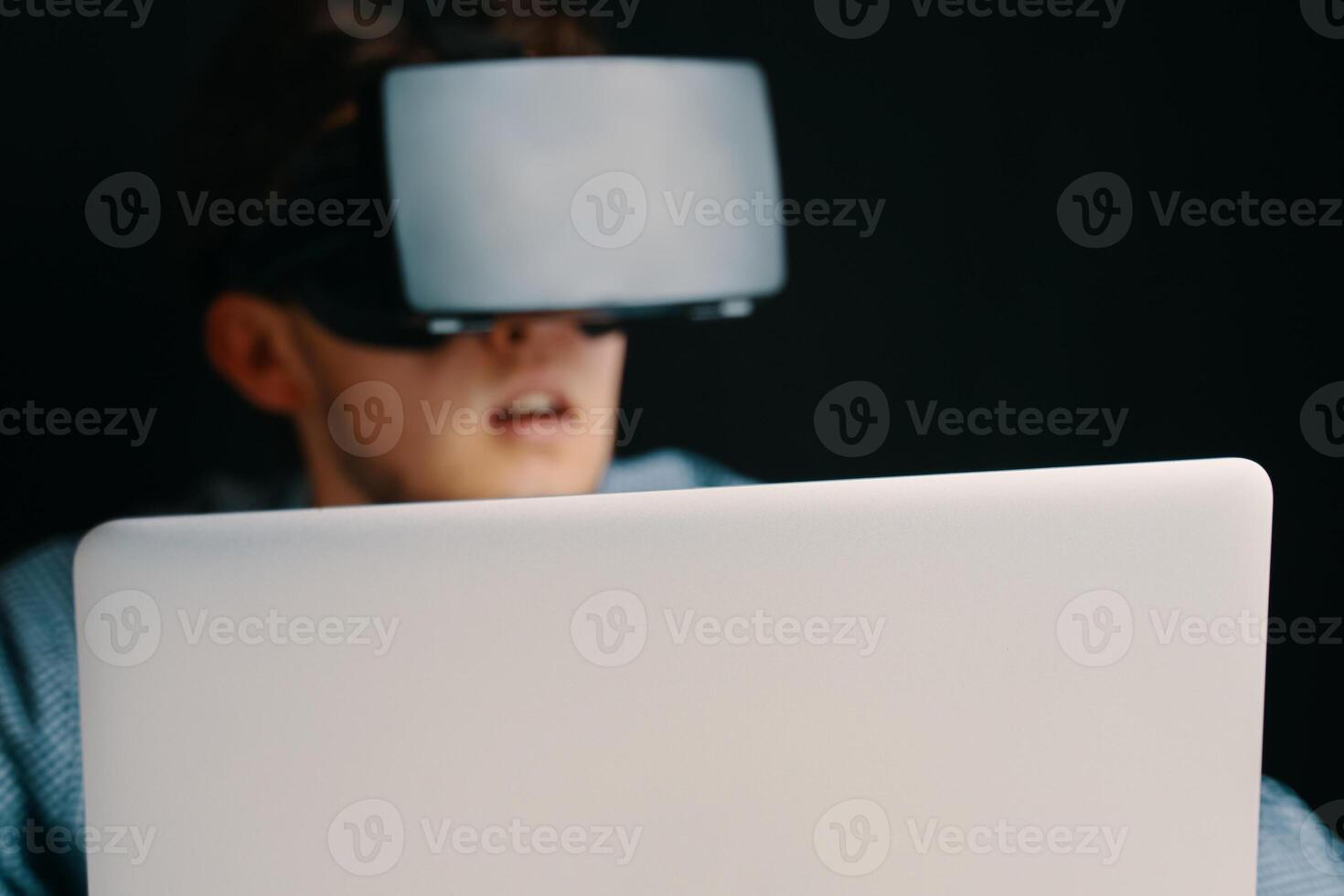 A young person in a VR headset with a laptop, symbolizing advanced technology and immersive digital experiences photo