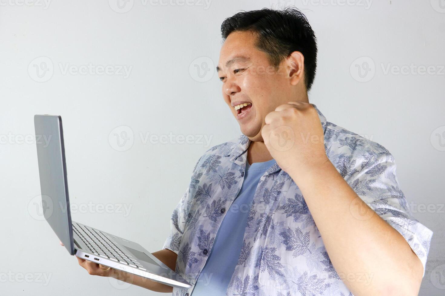 Excited Man Celebrating Success on Laptop and make a gesture of clenching his hand to say YES photo