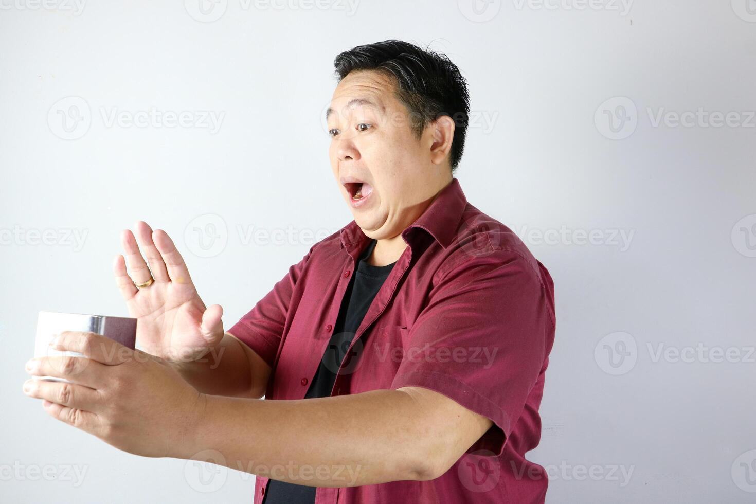 Man showing rejection gesture with his hand when holding a metal box, mouth open saying NO photo