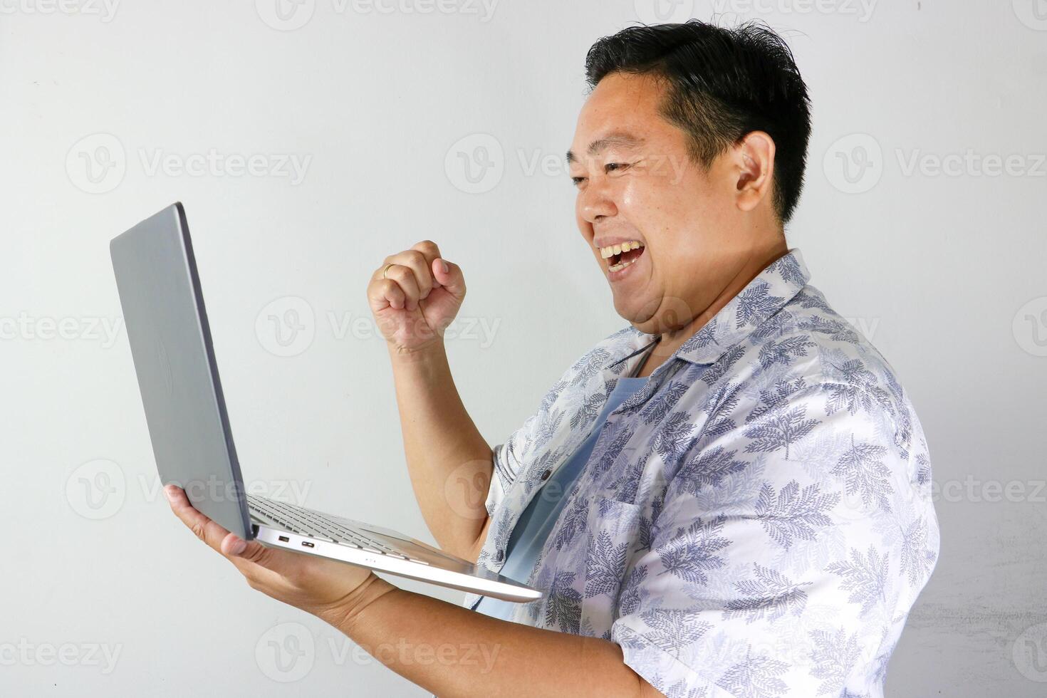 Excited Man Celebrating Success on Laptop with with clenched right hand photo