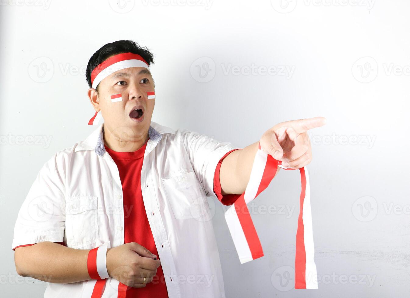 Excited Indonesian Fan wearing red and white headband pointing finger info copy space photo