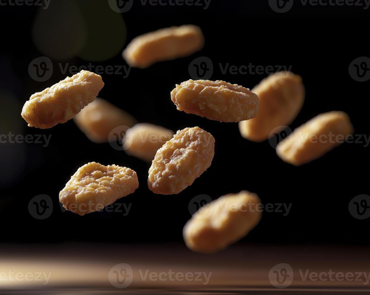 Crispy chicken nuggets falling in air on black background photo