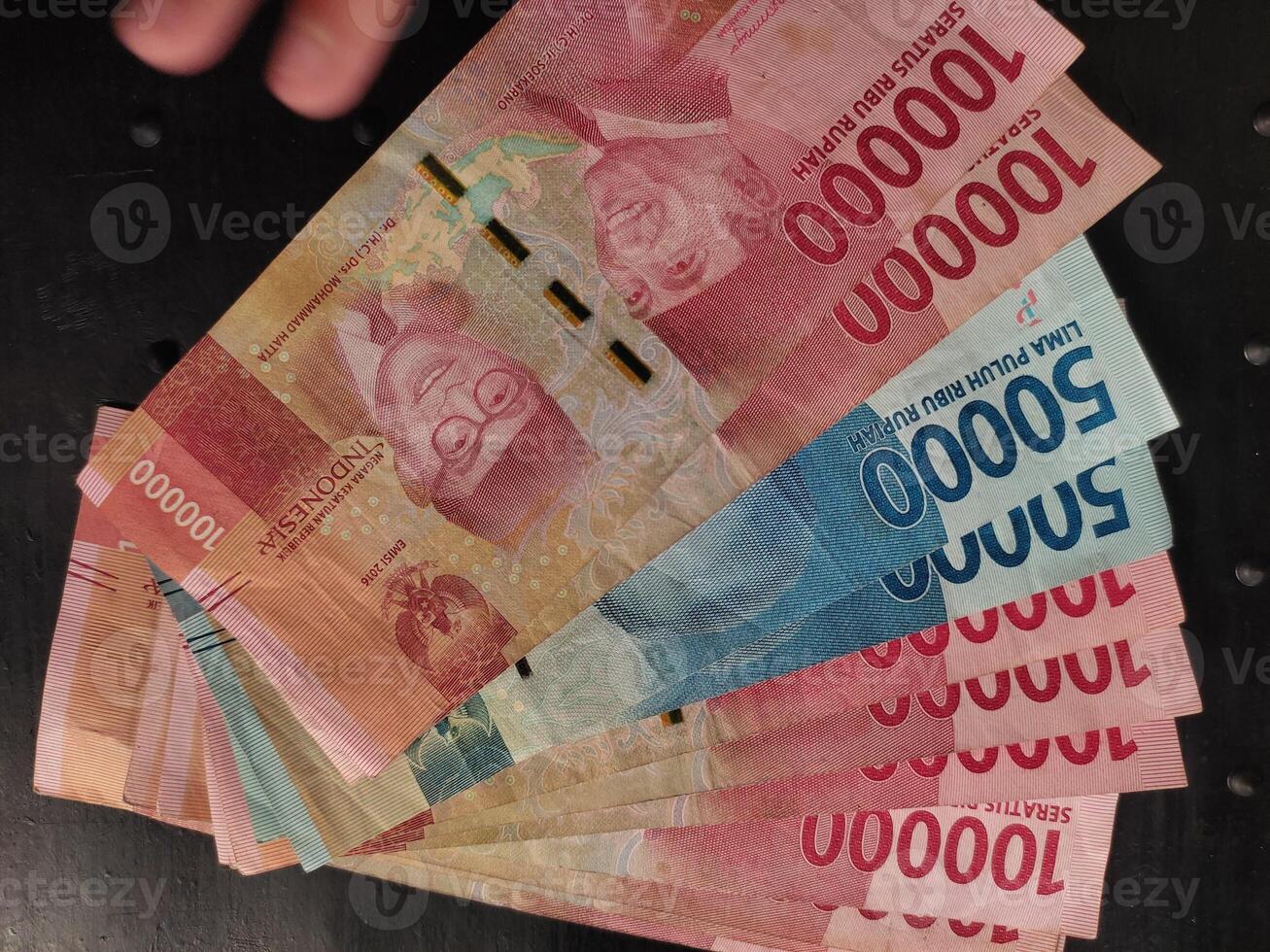 A close up view of Indonesia rupiah banknotes in various denominations, spread out against a dark black background photo