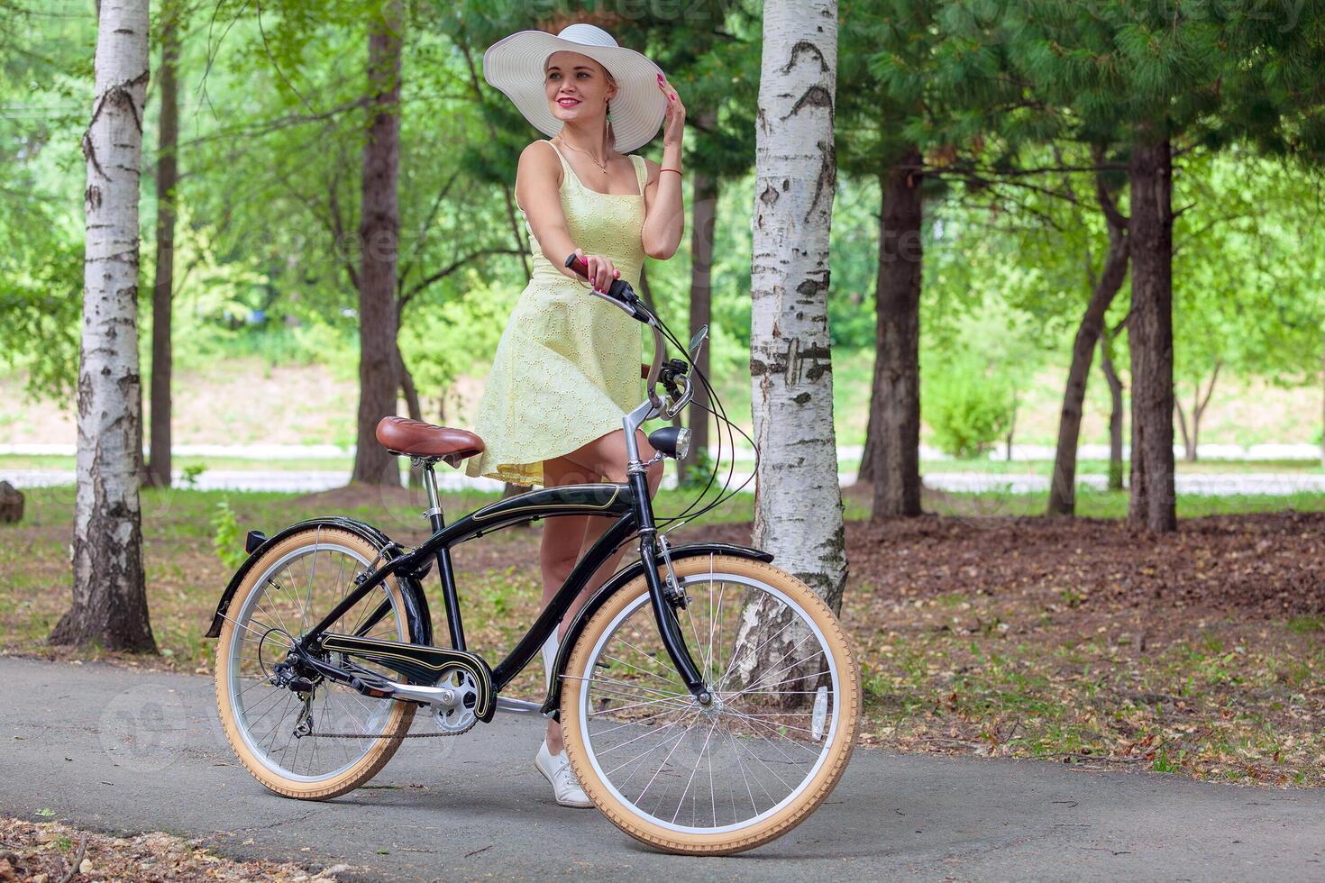 Beautiful young lady riding a bicycle in the park. Healthy lifestyle. photo