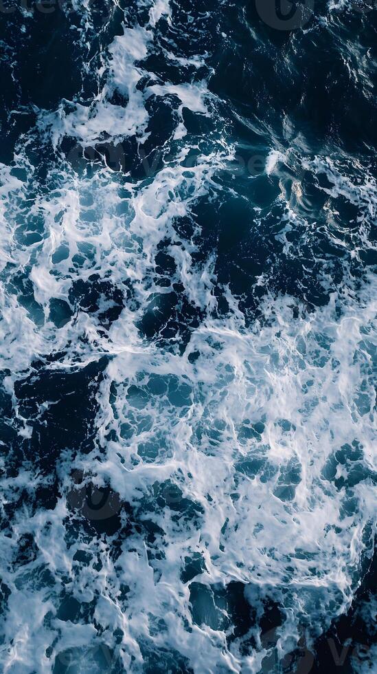 An aerial view of the ocean with white and blue waves photo