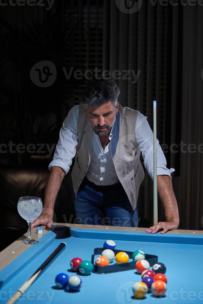 Gray haired billiard player thinking during pool game photo