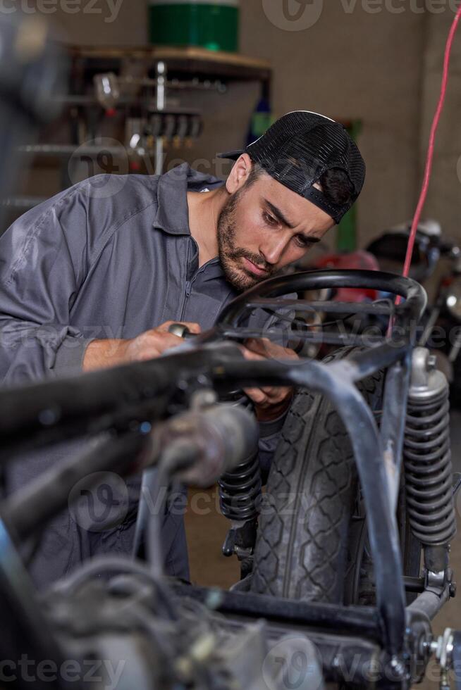 Serious male mechanic fixing motorbike in garage photo
