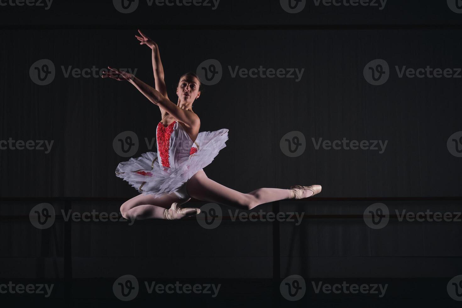 Flexible woman ballerina jumping while dancing ballet role photo